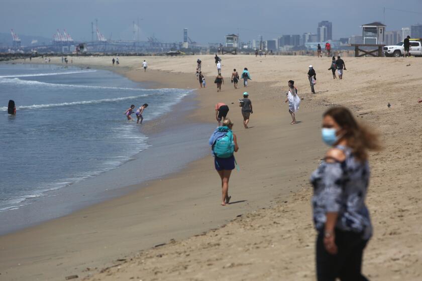 ORANGE COUNTY, CA - MAY 11: People walk at Seal Beach on Monday, May 11, 2020 in Orange County, CA. Seal Beach reopened to active use on Monday and will only be open during daylight hours Monday through Thursday. (Dania Maxwell / Los Angeles Times)