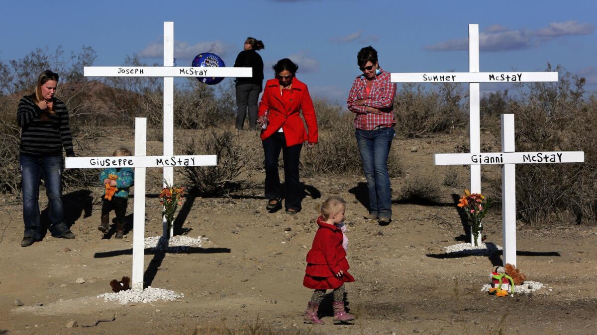 Family and friends pay respect at crosses erected in memory of Joseph and Summer McStay and their two children, who were found buried in shallow graves in Victorville in 2013.