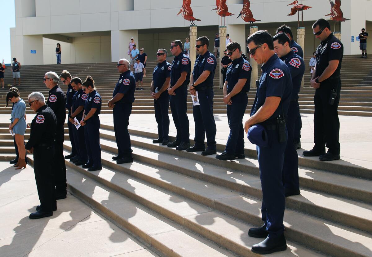 Firefighters bow heads in a moment of silence Sunday at a 9/11 ceremony outside Huntington Beach City Hall. 