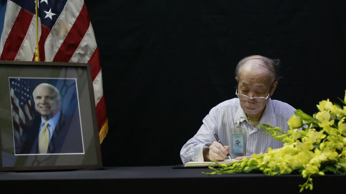 Pham Minh Chuc, an 81-year-old retiree, writes in a book of condolences for Sen. John McCain at the U.S. Embassy in Hanoi on Monday.