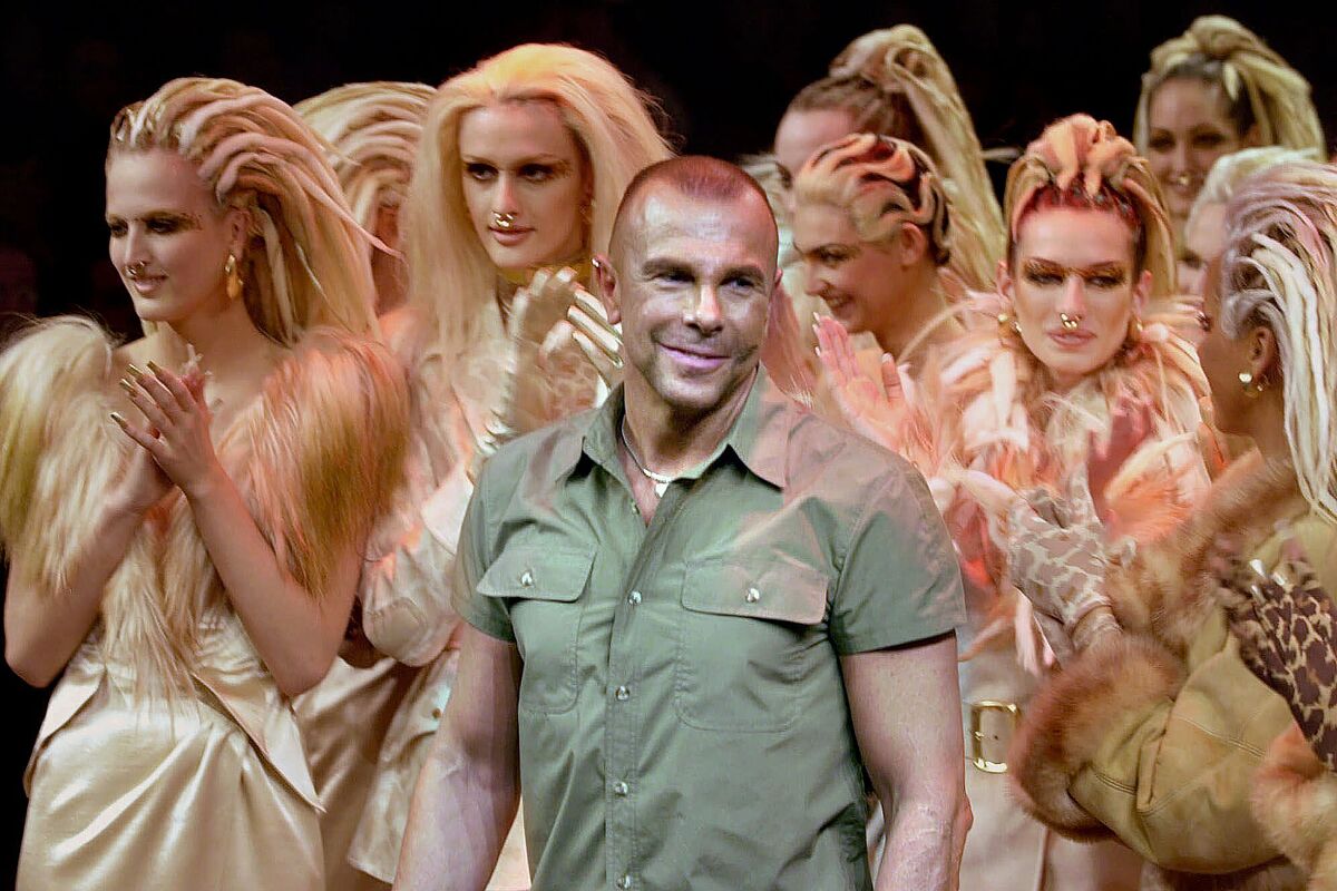 Manfred Thierry Mugler standing among a group of models wearing his designs