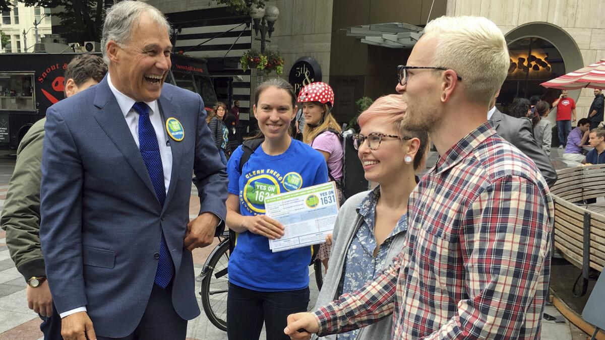 Washington Gov. Jay Inslee, left, helps gather signatures in Seattle for the carbon tax initiative.