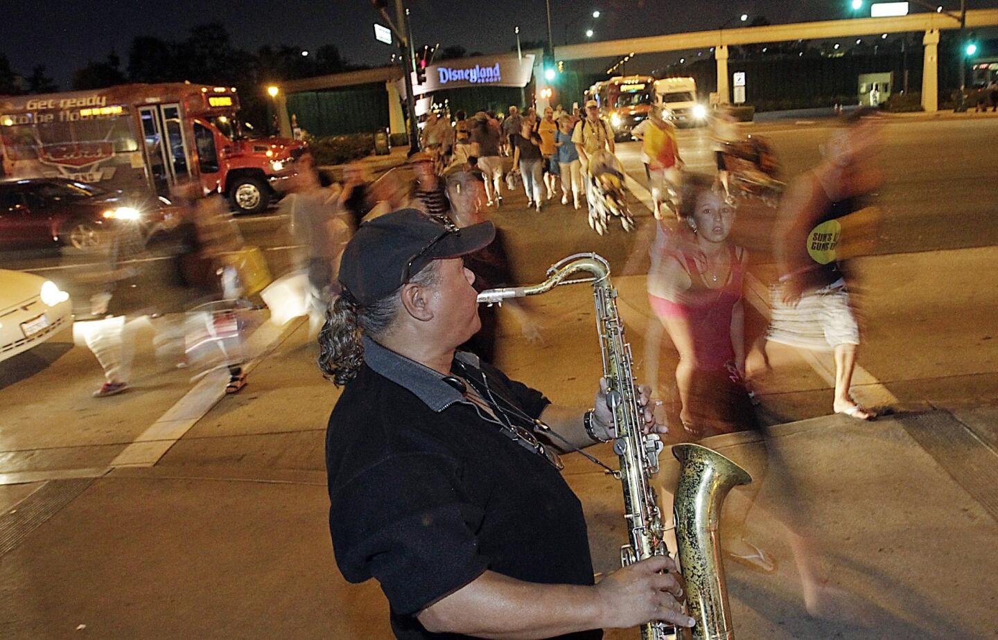 Mike the saxophone player gives a performance near Disneyland along Harbor Boulevard. Though the theme park has grown even more closed off from Anaheim over the years, its architecture has managed to seep out along the boulevard, where kitschy motels, lush landscaping and the monorail trumpet Disneyland's dominance.