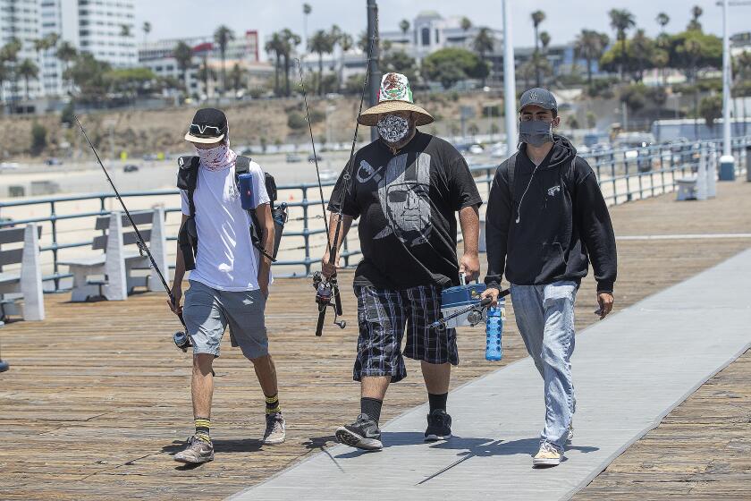 SANTA MONICA, CA - JUNE 29: Left to right-Friends Adrian Sanchez, 20, Matthew Gonzalez, 22, and Justice Arreola, arrive at the Santa Monica Pier in Santa Monica to do some fishing. They are all from Santa Monica. L.A. County is expected to reach 100,000 cases of coronavirus. (Mel Melcon / Los Angeles Times)