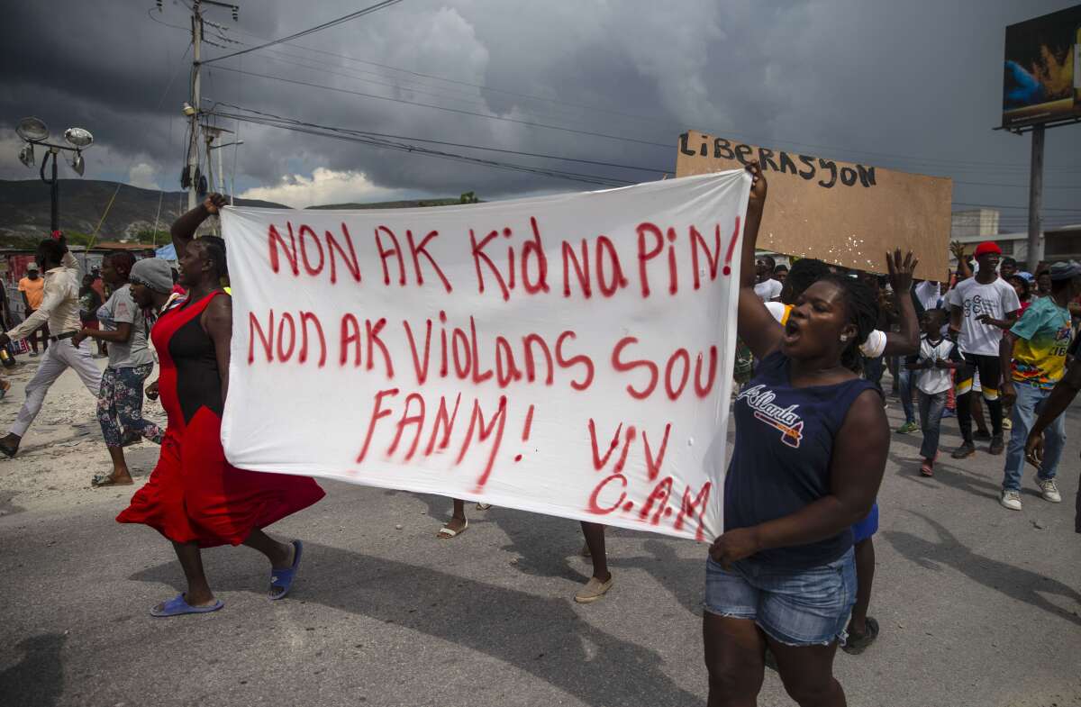 People in Haiti protest carrying a banner written in Creole.