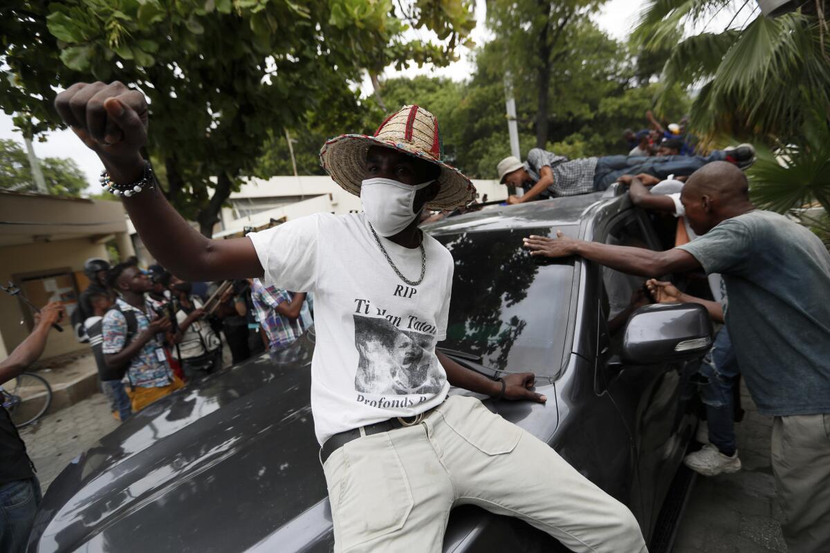 Supporters of former Senator Steven Benoit shout outside the courthouse as he departs after being called in for questioning, in Port-au-Prince, Monday, July 12, 2021. Prosecutors have requested that high-profile politicians like Benoit meet officials for questioning as part of the investigation into the assassination of President Jovenel Moise. (AP Photo/Fernando Llano)