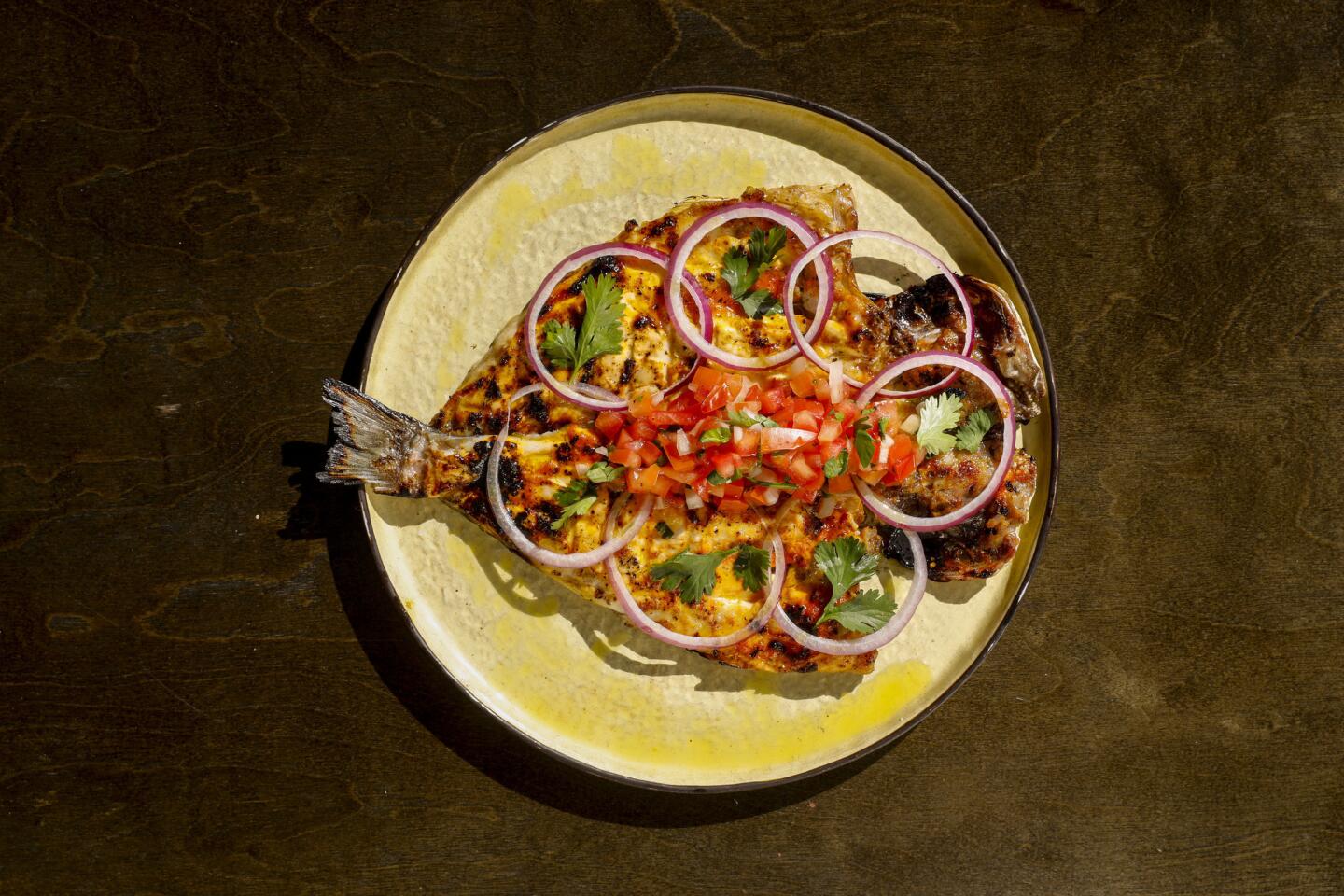 Pescado zarandeado, a 1.5-to-2-pound striped bass, cilantro, red onion, lemon, garlic, smoky chipotle, pico de gallo, corn tortillas, rice and beans.