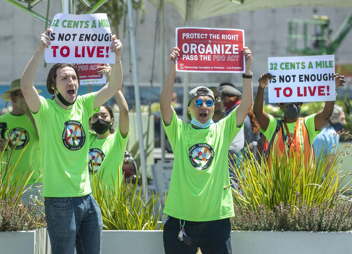 People in green shirts hold up protest signs.