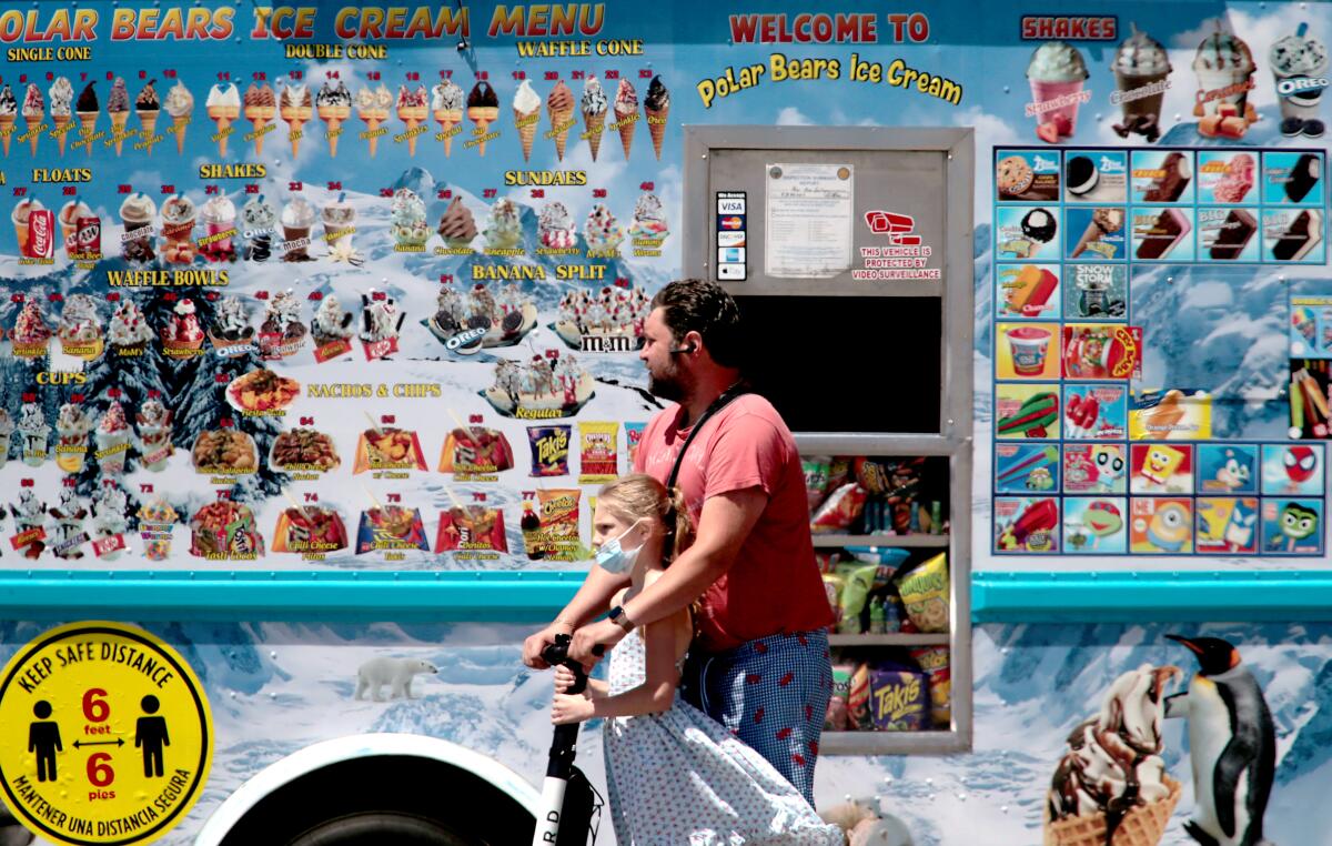Scooter riders zip past an ice cream truck at Alamitos Beach. 
