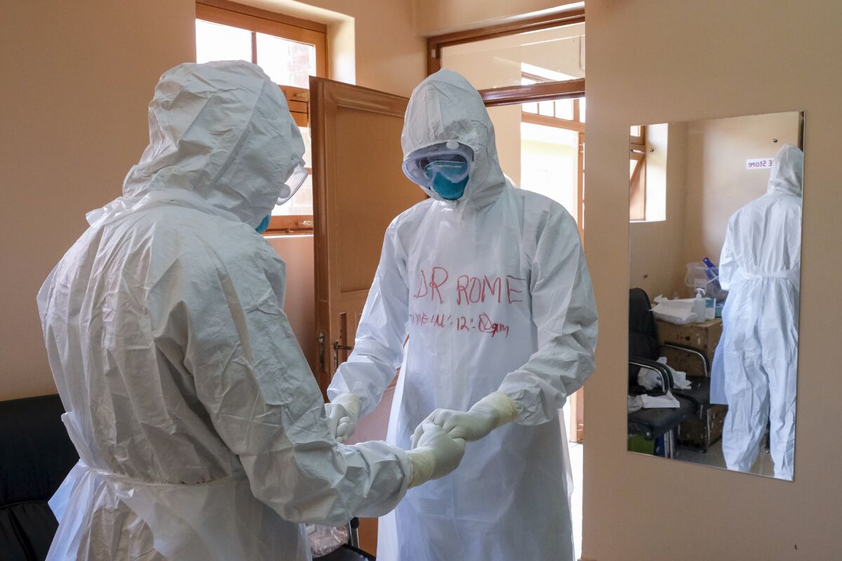 Médicos equipo de protección rezan antes de visitar a un paciente que estuvo en contacto con una víctima de ébola en la sección de aislamiento del Hospital de Referencia de Entebbe, en Entebbe, Uganda, el jueves de 20 de octubre de 2022. (AP Foto/Hajarah Nalwadda)