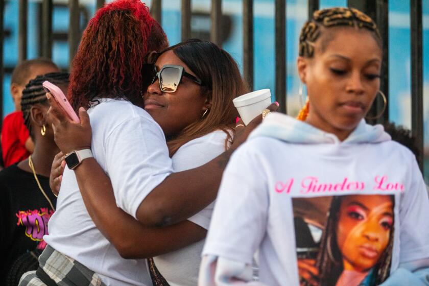 West Compton, CA - September 07: Ronnie Ramsey, left, hugs Tiffany Acker, middle, during a vigil for Tiffany's younger sister Asia Allen-Bookman on Thursday, Sept. 7, 2023, in West Compton, CA. Asia was one of the two people killed in a crash. Friends and family gathered at the location of the accident and held a vigil for Asia Allen-Bookman. (Francine Orr / Los Angeles Times)