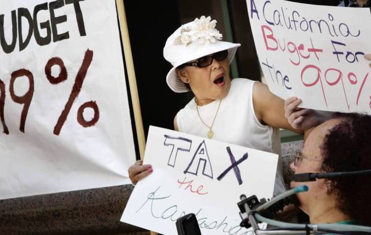 Christina Dorame holds a sign that reads "Tax the Kardashians" during a protest of Gov. Jerry Brown's revised budget in downtown L.A..