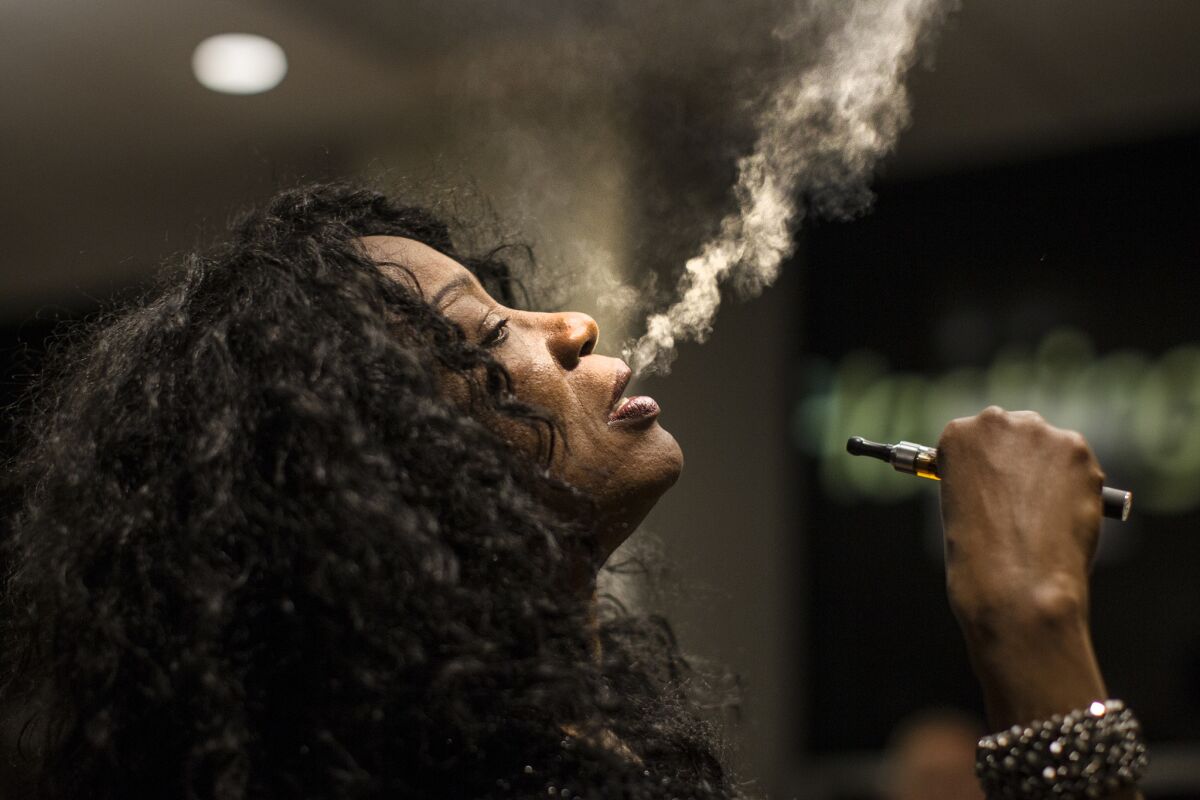 Singer Linda Evans blows vapor from an electronic cigarette to calm her nerves before performing with her chorus made up of singers from skid row in a gala at the City Club in 2014.
