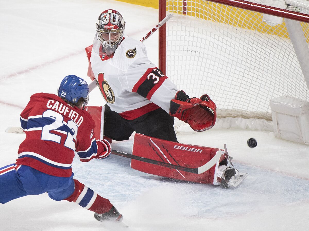 Montreal Canadiens' Cole Caufield scores against Ottawa Senators' goaltender Filip Gustavsson during overtime of an NHL hockey game in Montreal, Saturday, May 1, 2021. (Graham Hughes/The Canadian Press via AP)