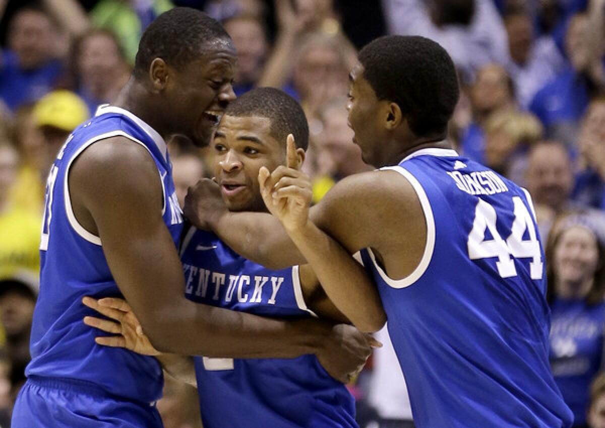 Kentucky forward Aaron Harrison is congratulated by teammates Julius Randle (left) and Dakari Johnson (44) after making a three-point shot with 2.3 seconds left to clinch a victory over Michigan in the Midwest Regional final on Sunday in Indianapolis.