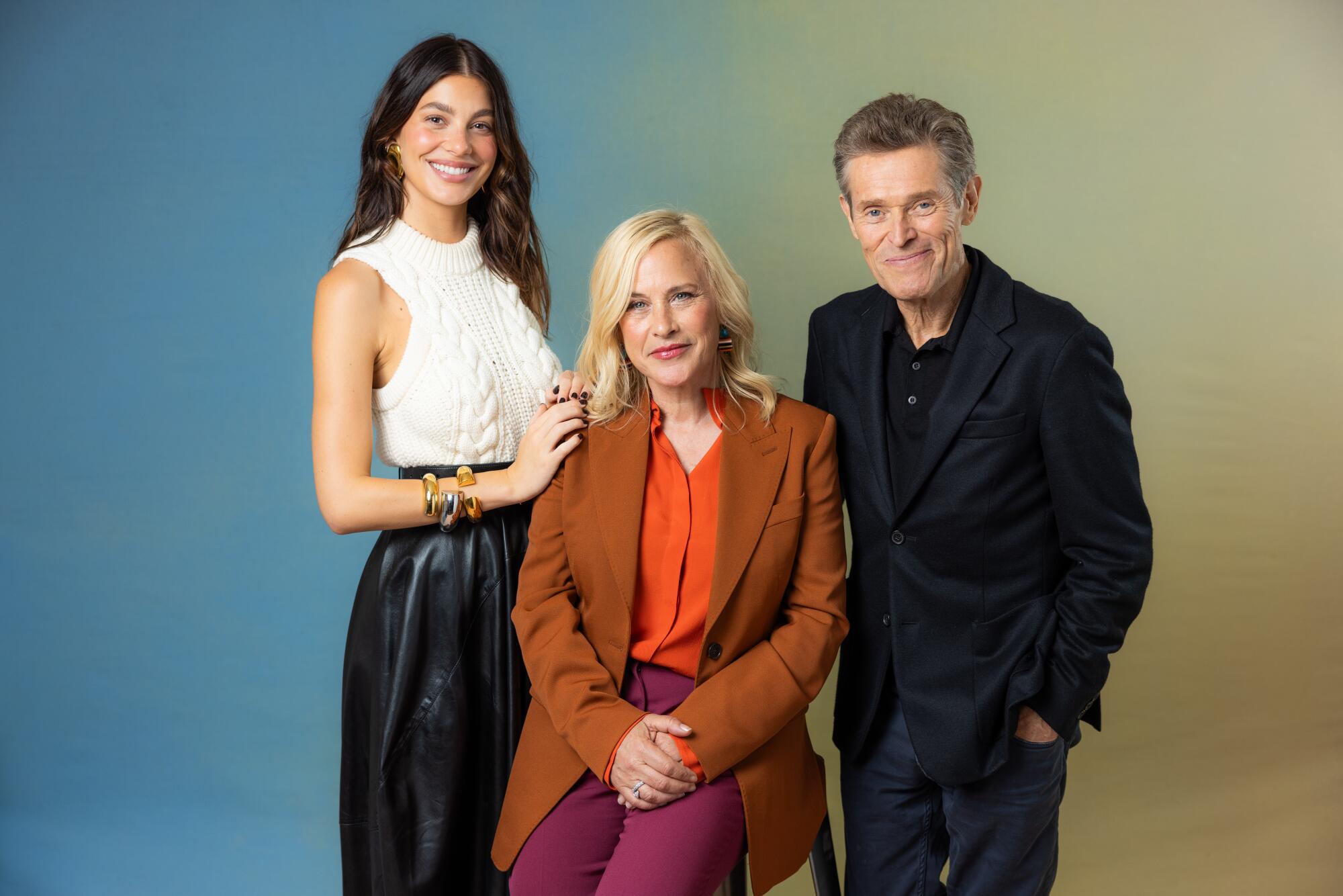 Camila Morrone, Patricia Arquette and Willem Dafoe pose together and smile.