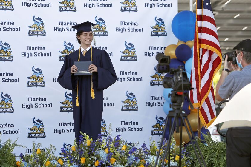 Ilhan Bronja poses with his diploma during a drive-through graduation ceremony for Marina High School in Huntington Beach on Thursday.