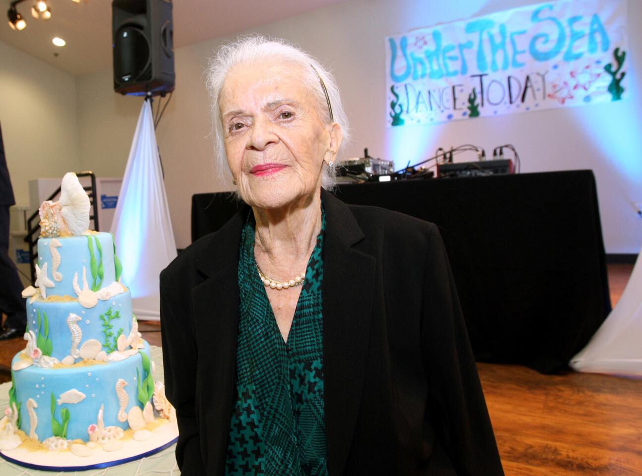 Gloria Aguirre, 92 of Glendale, poses in front of a large birthday cake during party for 90-year olds at the Adult Recreation Center in Glendale on Thursday, May 19, 2016.