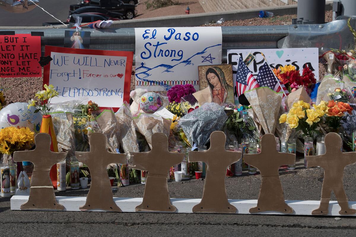 Signs, flowers, flowers, U.S. flags and an image of the Virgin Mary at a makeshift memorial for El Paso shooting victims.
