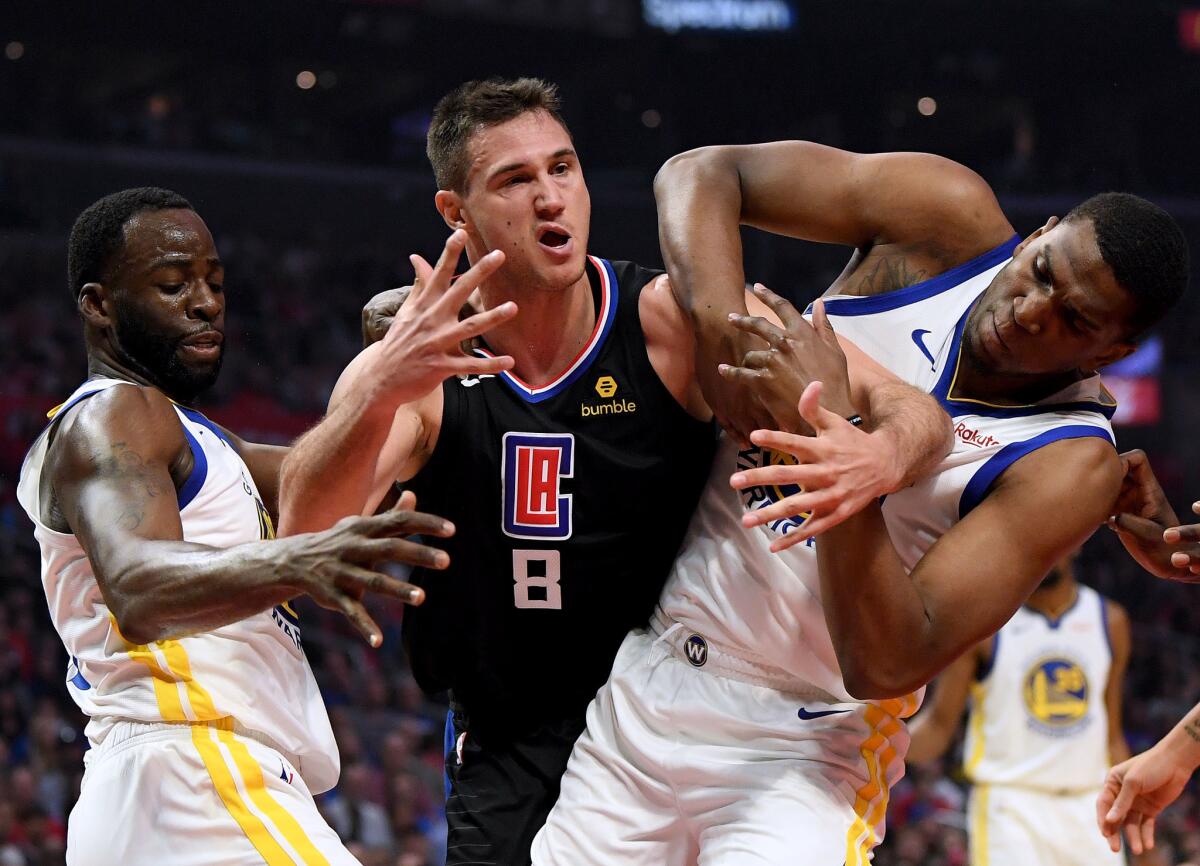 Danilo Gallinari #8 of the LA Clippers gets tangled with Kevon Looney #5 and Draymond Green #23 of the Golden State Warriors during the first half in Game Four of Round One of the 2019 NBA Playoffs at Staples Center on April 21, 2019 in Los Angeles, California.