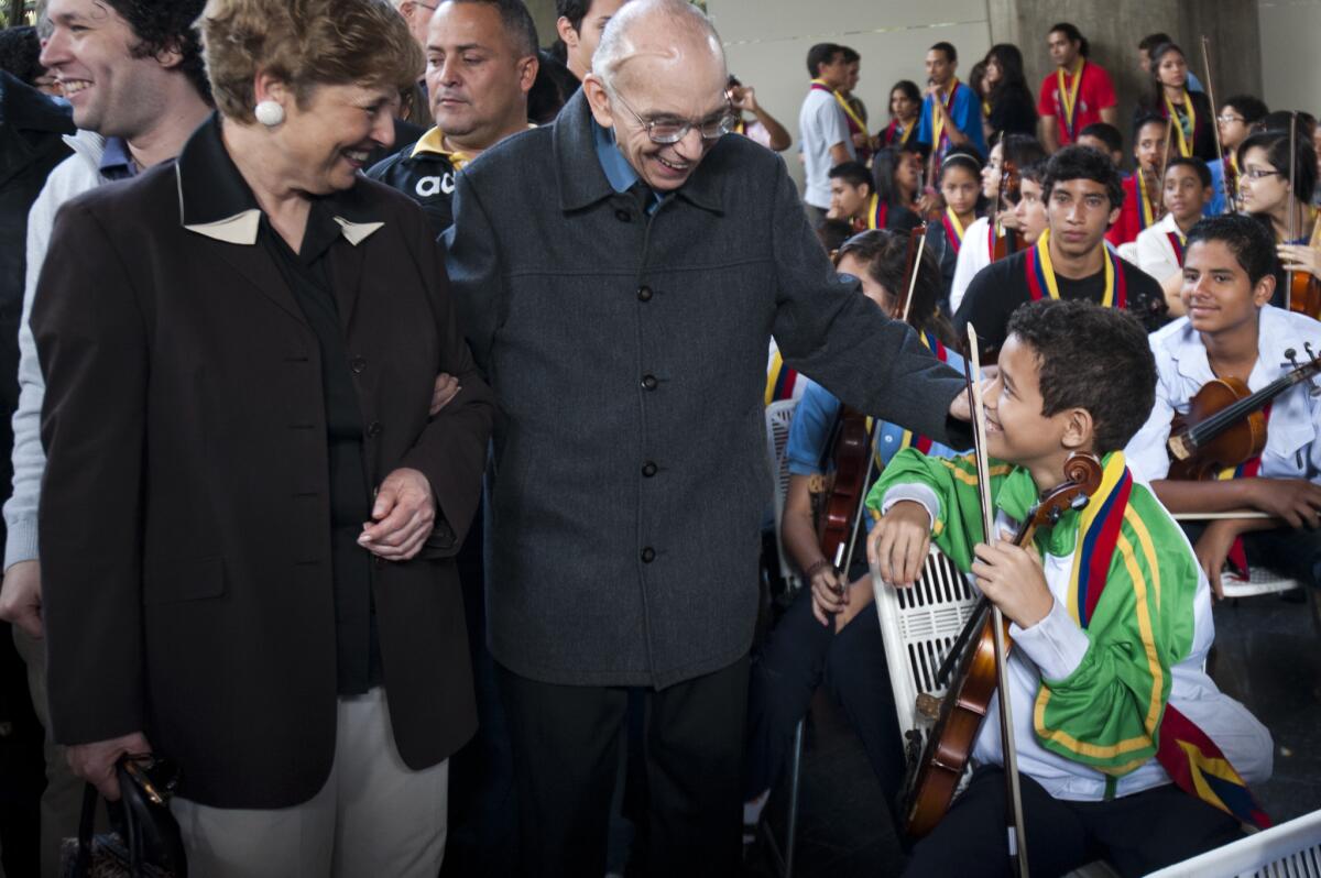 The founder of the National System of Children and Youth Orchestras, Jose Antonio Abreu, and the president and chief executive officer of Los Angeles Philharmonic, Deborah Borda, greets a young Venezuelan musician during a concert by the Simon Bolivar Youth Symphonic Orchestra in Caracas in 2012.