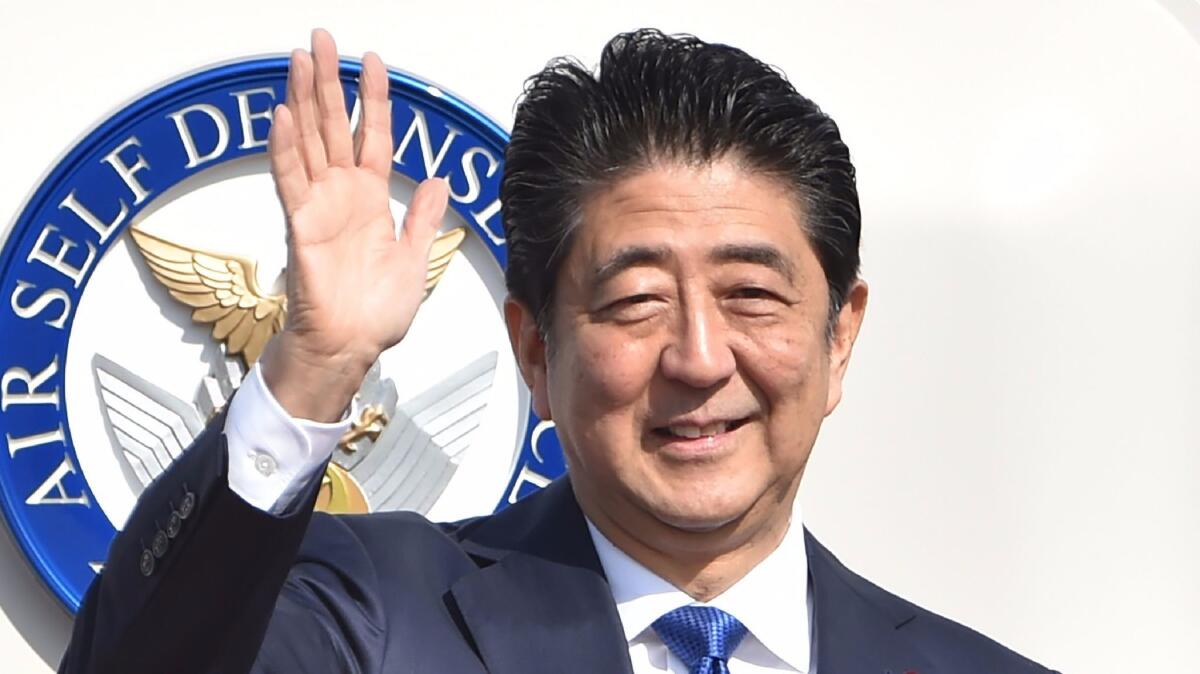 Japanese Prime Minister Shinzo Abe waves to well-wishers before boarding a plane in Tokyo on Nov. 17, 2016.
