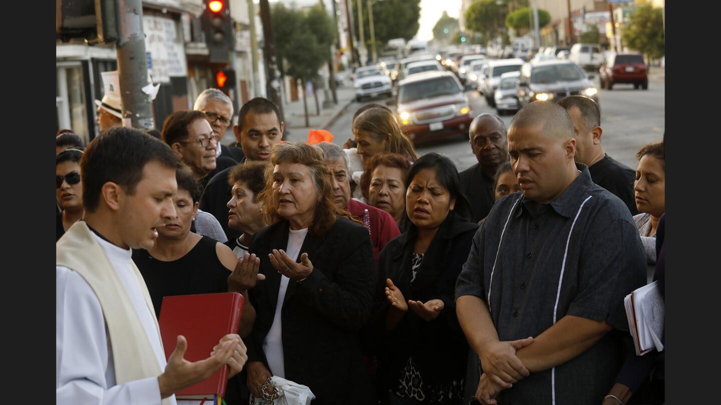 Father Parker Sandoval, left, prays at a vigil for Jose Luis Hernandez, 7, and his brother Marcos, 9, who were killed Thursday after they were struck by an L.A. County Sheriff’s Department vehicle that careened onto a sidewalk after a crash in Boyle Heights. Their mother, who was also hit, remains in critical condition.