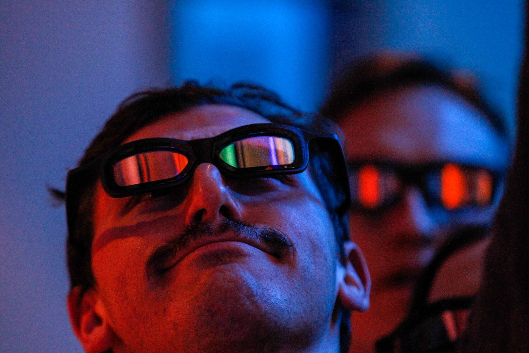A man wearing 3-D glasses and looking up.