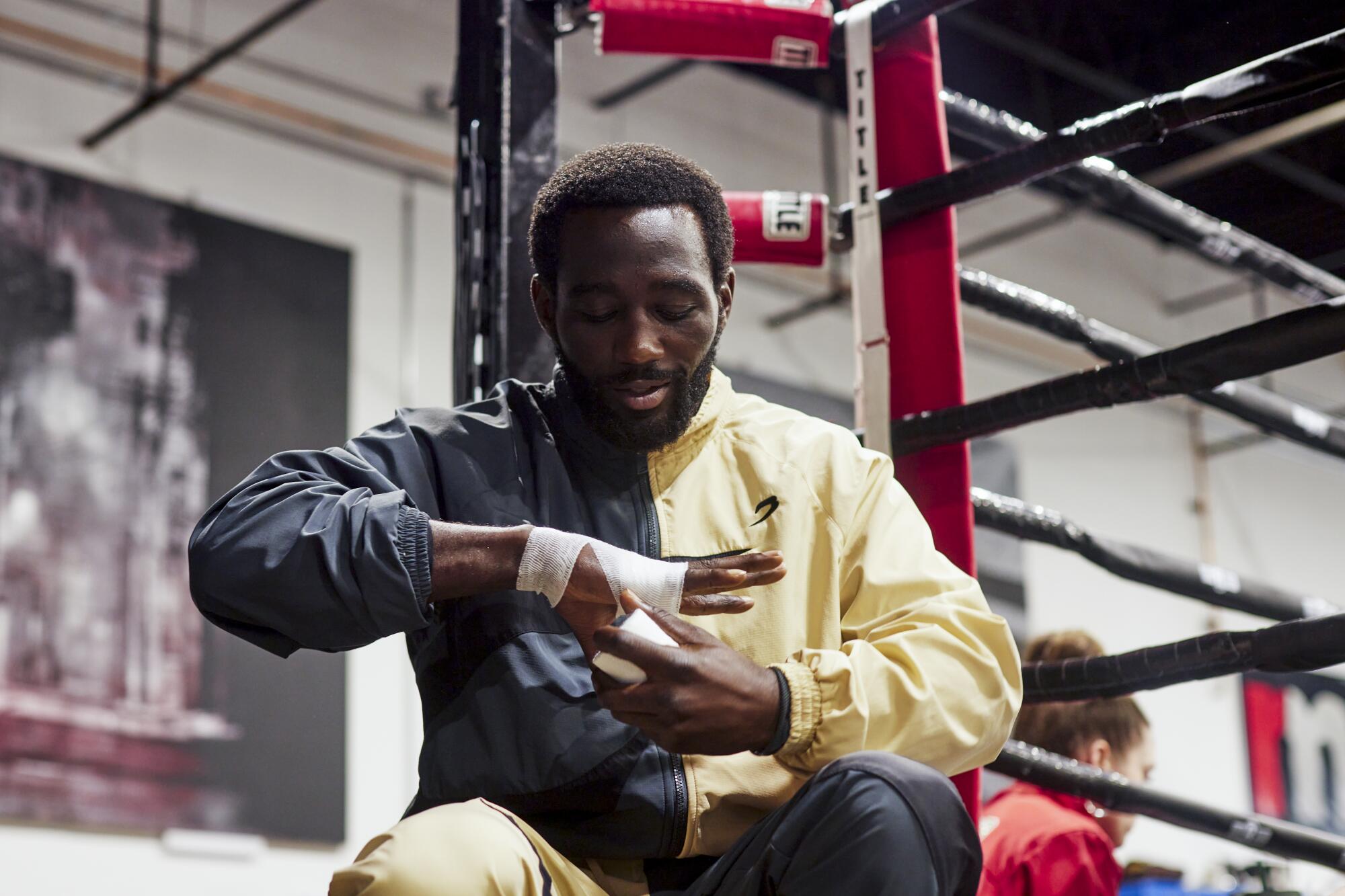 Terence 'Bud' Crawford wraps tape around his hands while standing outside a ring, getting ready to train