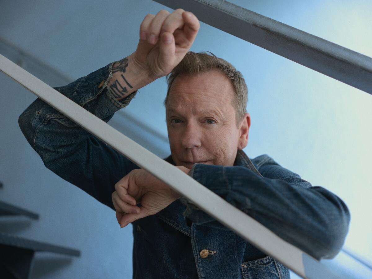 Kiefer Sutherland leans on the stair railing to take a portrait.