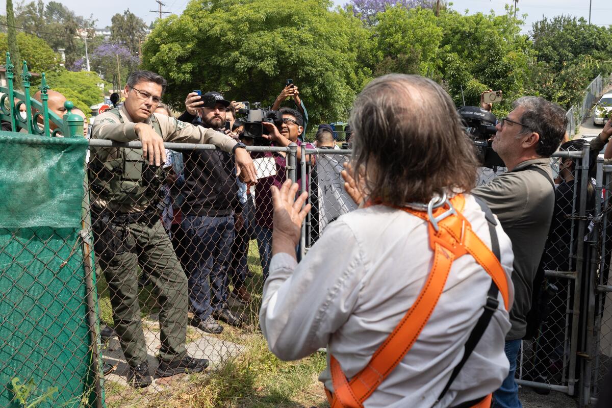 Sheriff's deputies speak to men on the fence while the crowd is watching