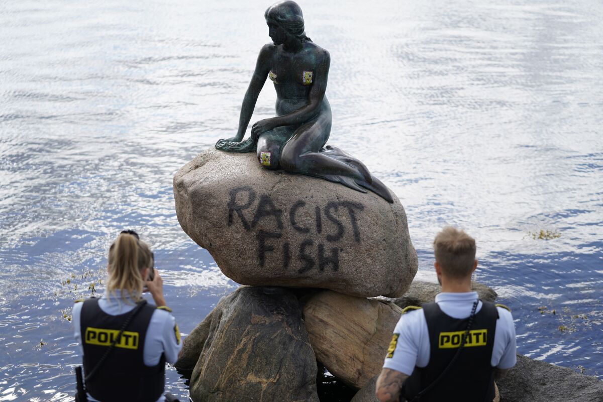 Police stand by the statue of the Little Mermaid, after it was vandalized, in Copenhagen, Denmark, Friday, July 3, 2020. The famed statue of Hans Christian Andersen’s Little Mermaid, one of Copenhagen’s biggest tourist draws, has been vandalized ... again. The text “racist fish” was tagged on the stone of which the oft-attacked 1.65-meter (5.4-foot)-high bronze is sitting on at the entrance of the Copenhagen harbour, the Ekstra Bladet daily reported. No one has taken responsibility for the act. (Mads Claus Rasmussen/ Ritzau Scanpix via AP)