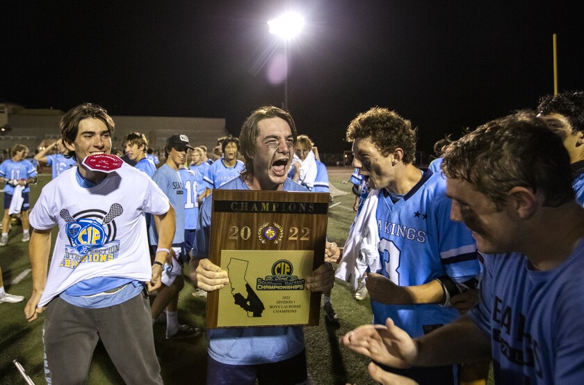 Corona del Mar's Lucas Newton celebrates with the championship plaque after beating Foothill in the  boys' lacrosse final.