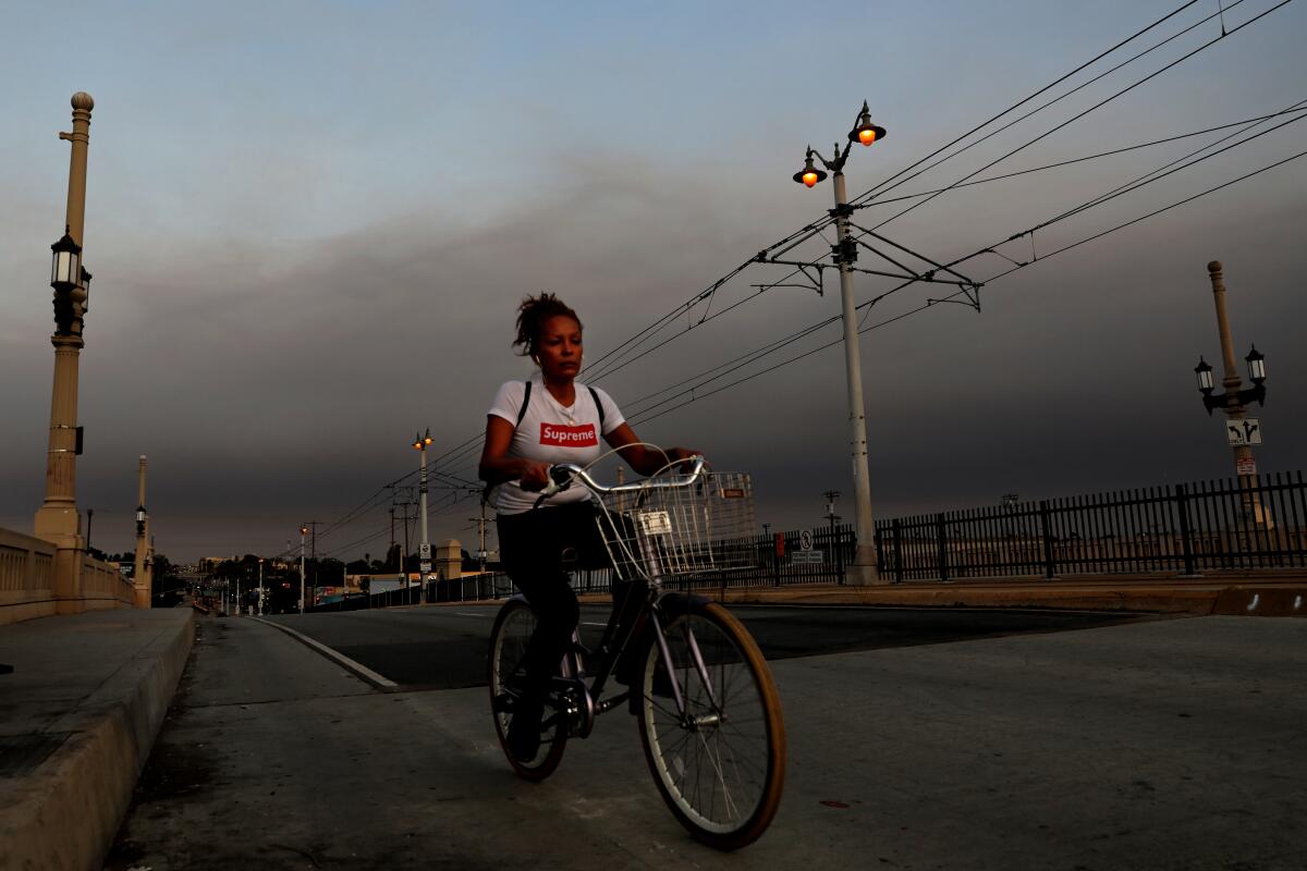 A bicyclist rides along 1st Street Bridge in Los Angeles under smoky skies.