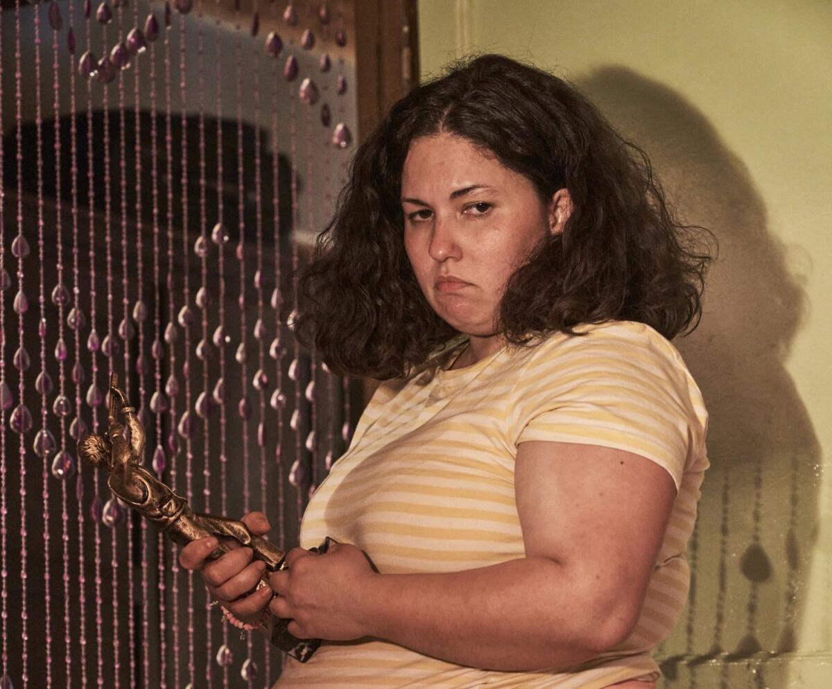 A woman holds a metal figure in the movie "Piggy."