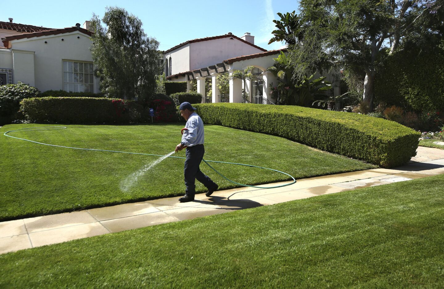 A gardener waters the front lawn of a home in Beverly Hills.