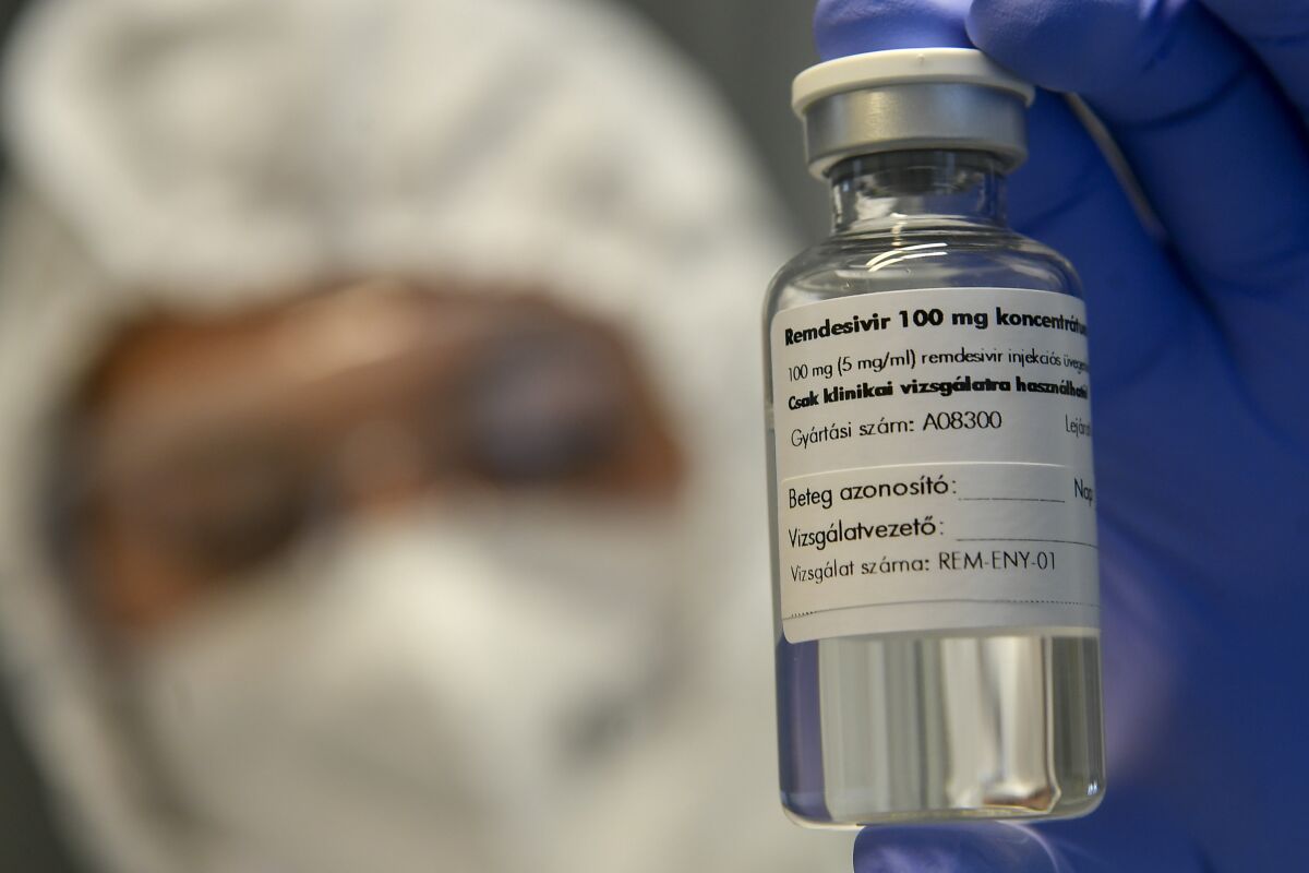 A healthcare worker holds a vial of the drug remdesivir