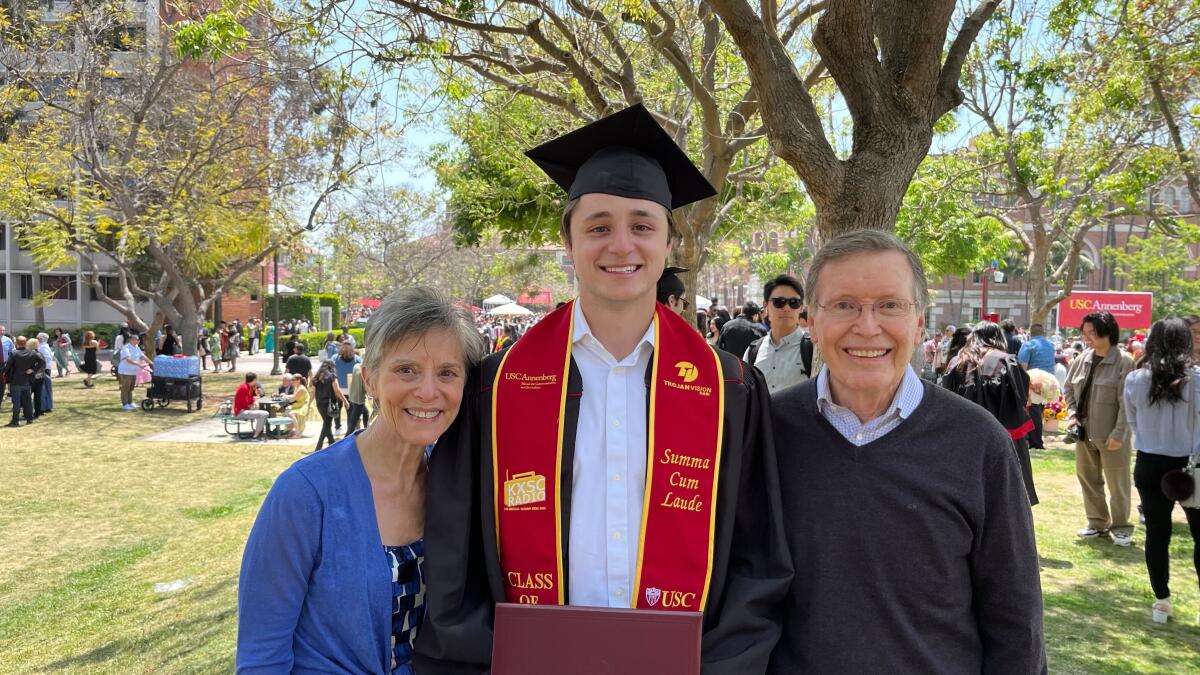 Clippers broadcaster Carlo Jiménez wears a cap and gown while standing beside his grandparents after his USC graduation