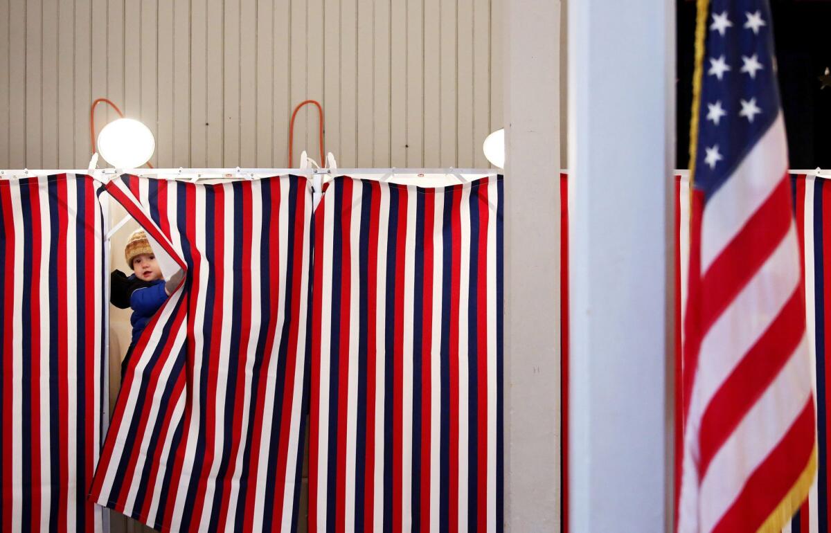 Thirteen-month-old Joseph Chichester peeks out of a voting booth as his father, Luke, casts his ballot in Tuesday's presidential primary in Greenfield, N.H.