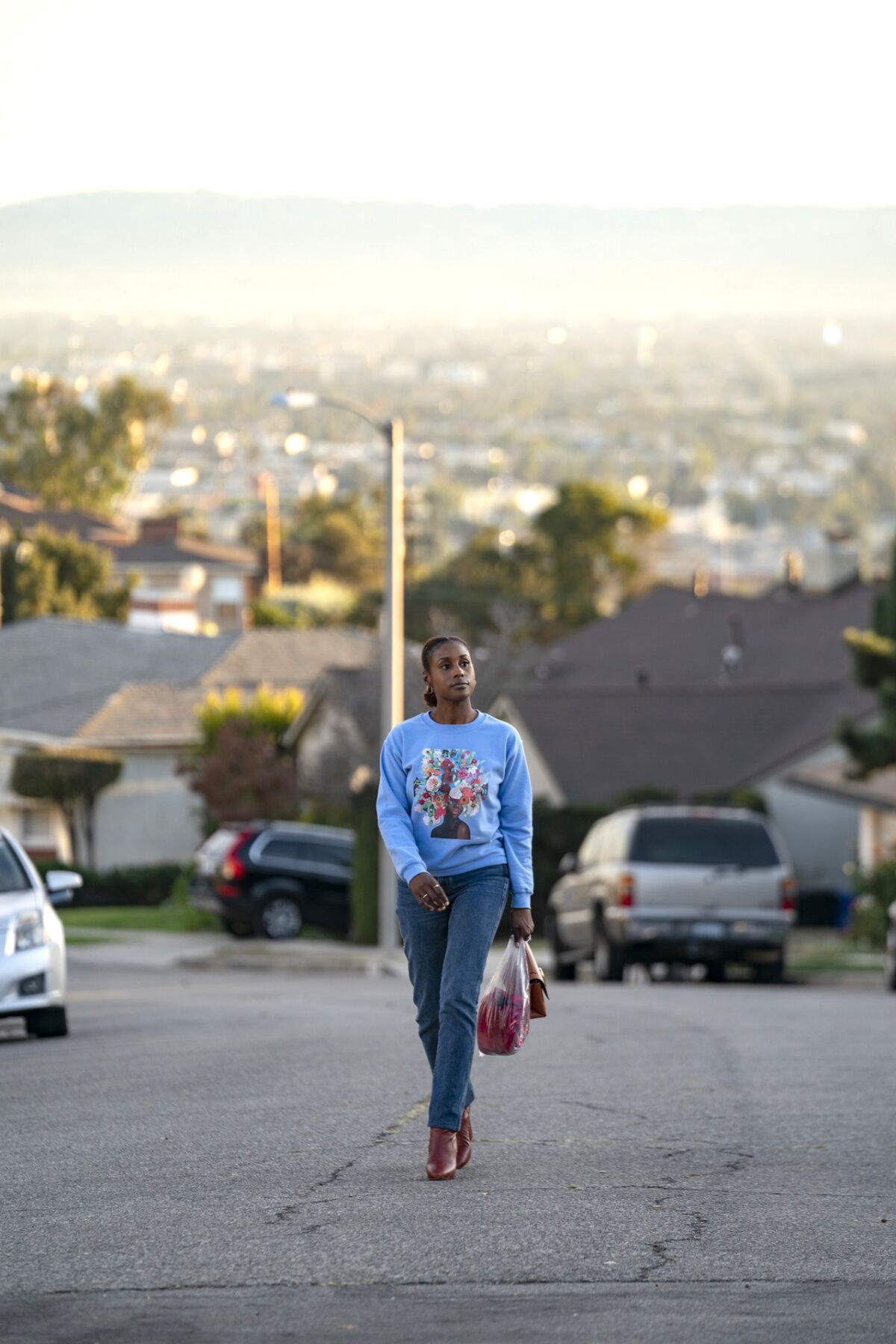 A woman walks up the middle of a street in Los Angeles