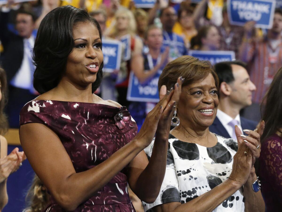 Michelle Obama and her mother, Marian Robinson, clap amid a large crowd.
