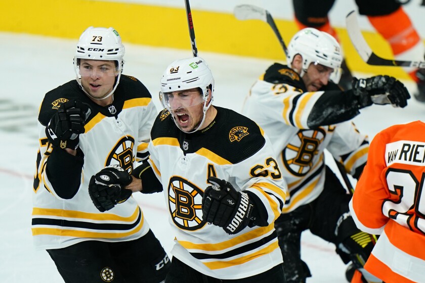 Boston Bruins' Brad Marchand (63) celebrates with Charlie McAvoy (73) after scoring a goal during the third period of an NHL hockey game against the Philadelphia Flyers, Friday, Feb. 5, 2021, in Philadelphia. (AP Photo/Matt Slocum)