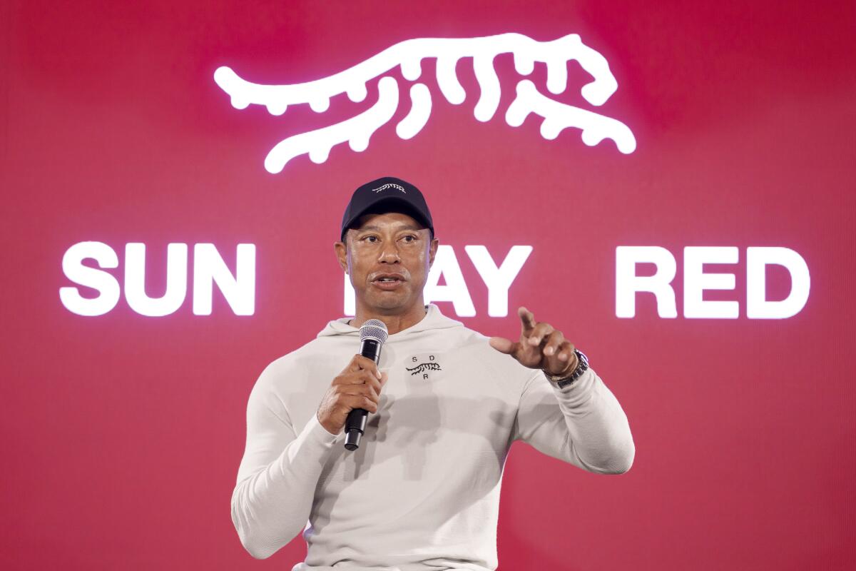 Tiger Woods in front of a red backdrop with the words 'Sun Day Red' and a tiger logo