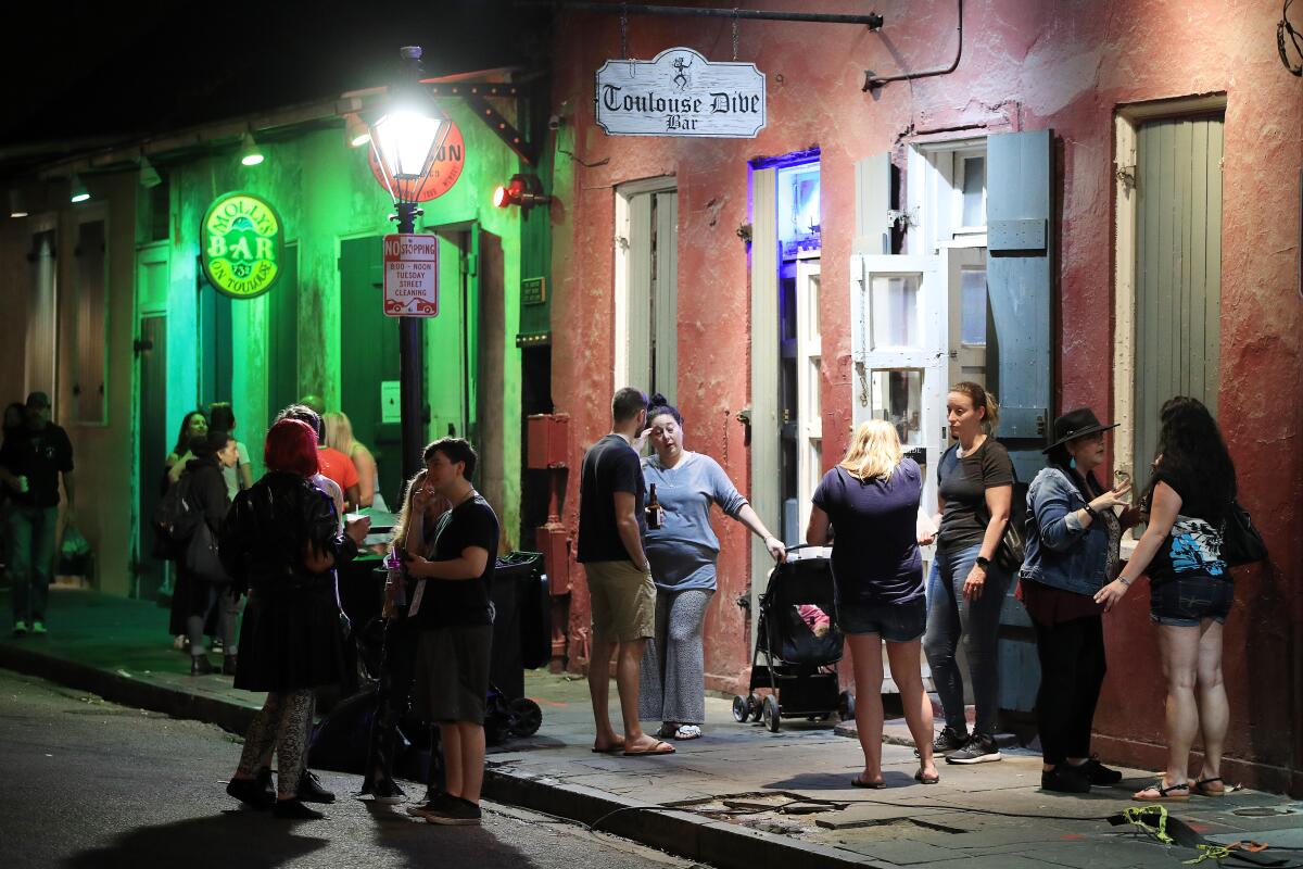 People stand outside a bar just off of Bourbon Street