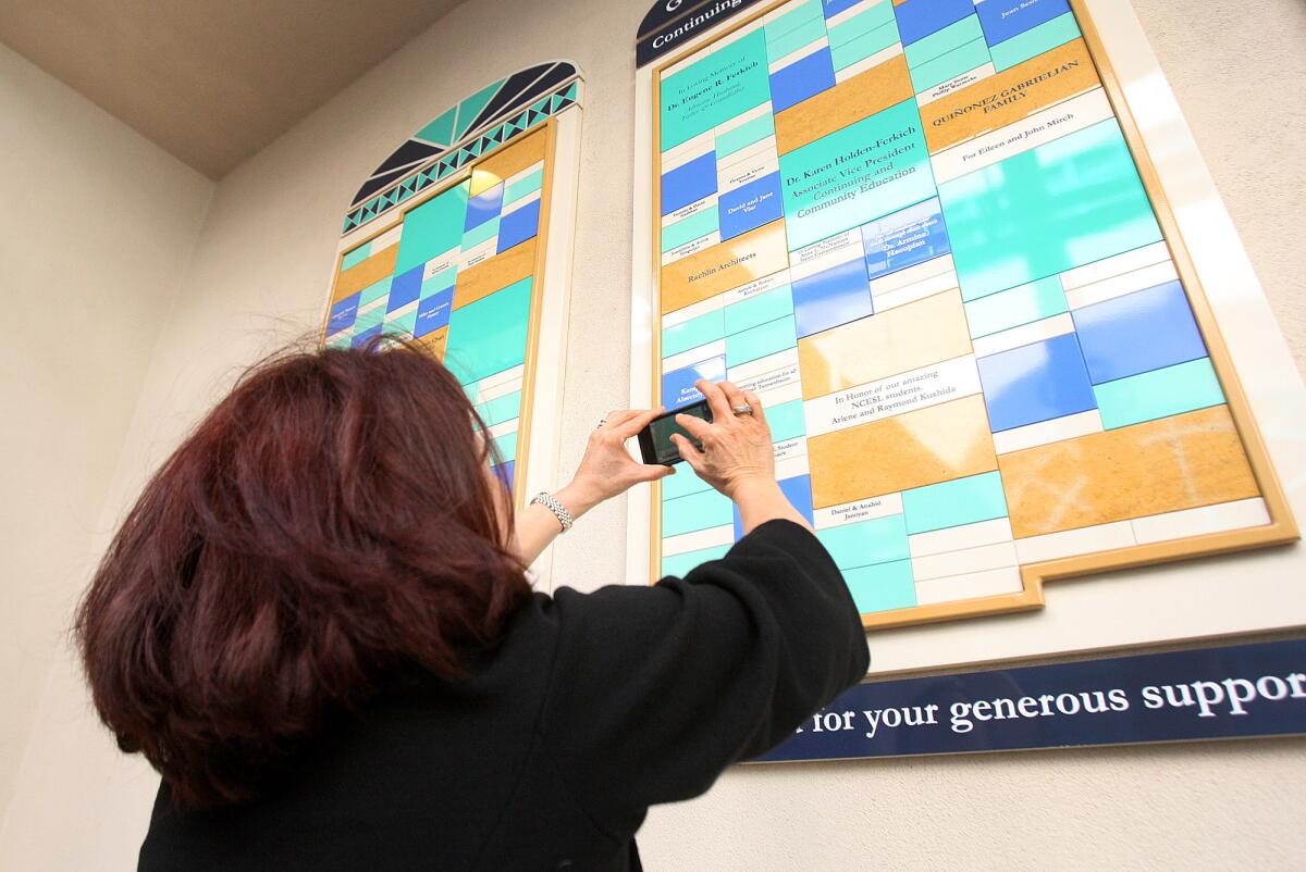 Giselle Acevedo of New York takes a picture of a tile with her mom Lidia Madrigal's name at the unveiling of the Garfield Campus Donor Wall on Monday, March 17, 2014.