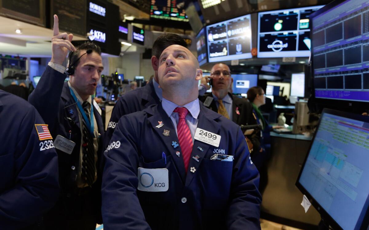 Specialist John Parisi, center, works at his post on the floor of the New York Stock Exchange Monday.