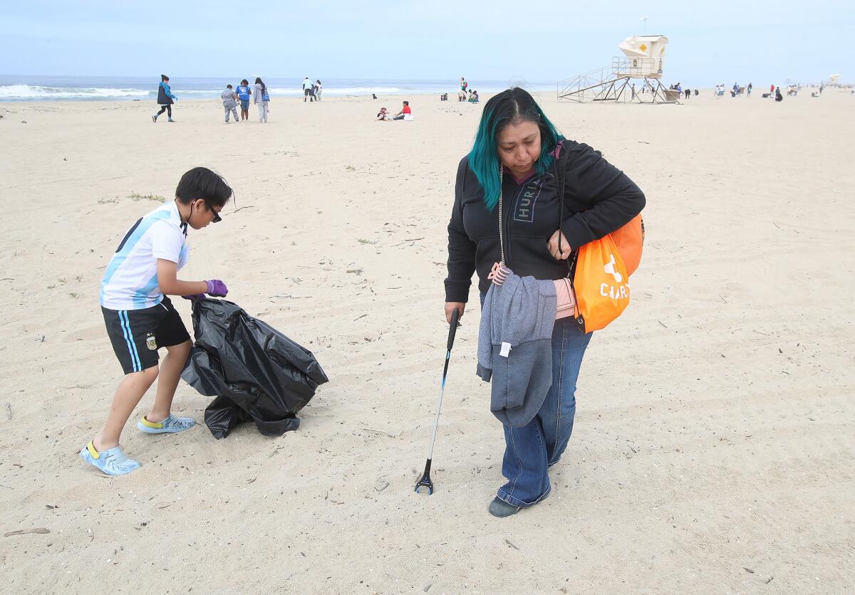 Mona Sharia looks for pieces of plastic from the sand.