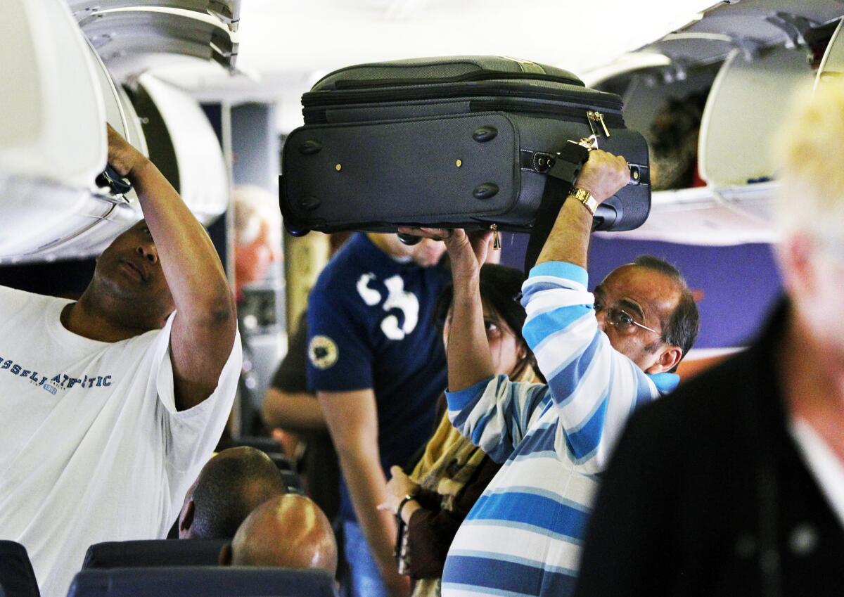 A Southwest Airlines passenger stows his luggage before a flight from Midway Airport in Chicago to Cleveland in 2010. Airfares could drop by 5% next year, according to an airline trade group.
