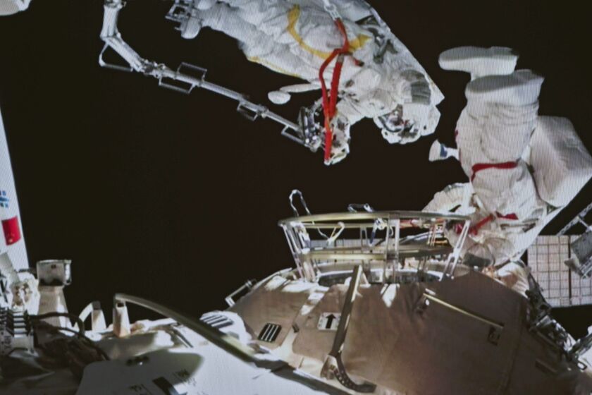 In this image released by the Xinhua News Agency, a photo taken on a screen shows Chinese astronauts Zhai Zhigang and Wang Yaping conducting extravehicular activities outside the space station's Tianhe core module, from the Beijing Aerospace Control Center on Sunday, Nov. 7, 2021. Wang Yaping has become the first Chinese woman to conduct a spacewalk as part of a six-month mission to the country's space station. Wang and fellow astronaut Zhai Zhigang left the station's Tianhe core module on Sunday evening Beijing time, spending more than six hours installing equipment and carrying out tests alongside the station's robotic service arm. (Guo Zhongzheng/Xinhua via AP)