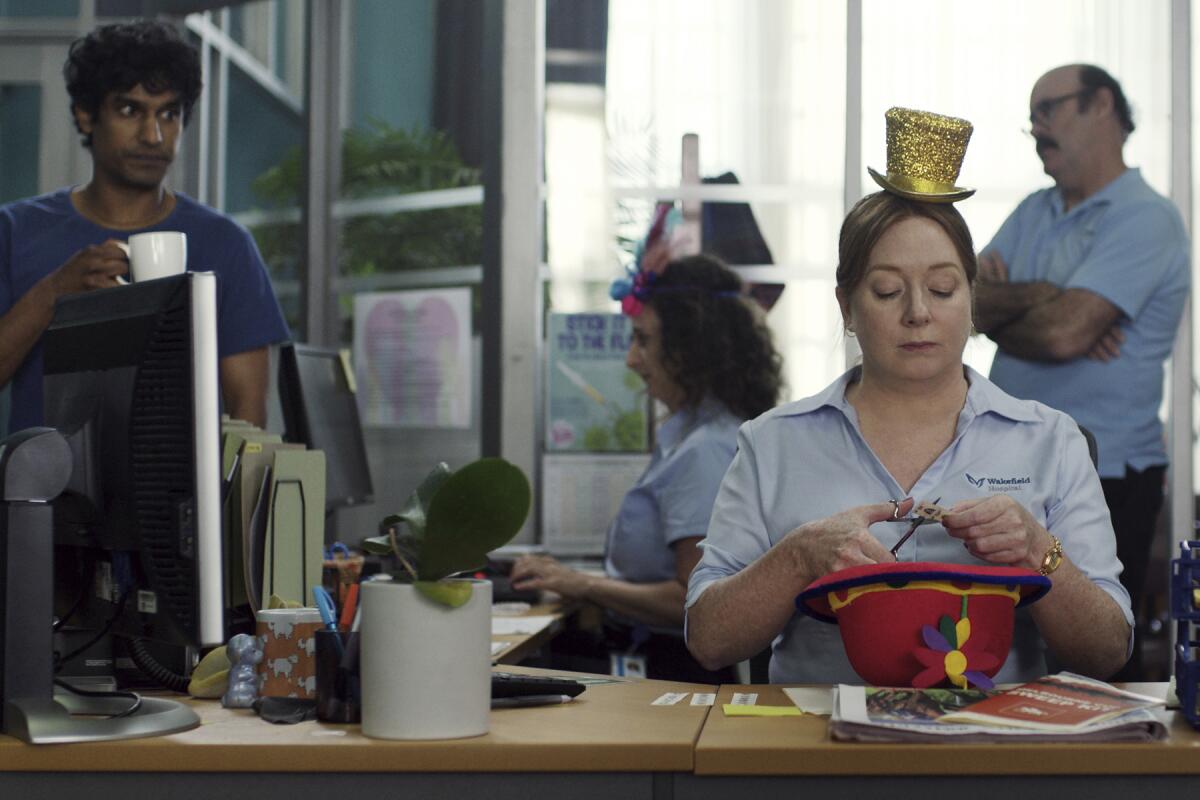 A woman works on a hat as a co-worker looks on